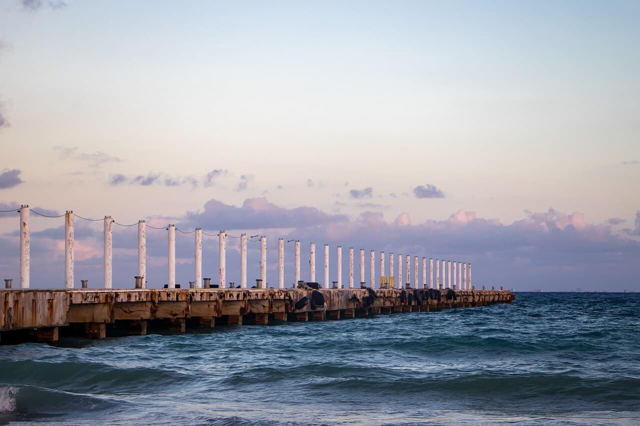 A scenic view of the pier at Playa del Carmen, Mexico, overlooking the turquoise sea under a clear sky